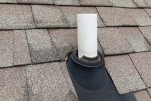 Two people measuring the slope of a residential roof with snow visible on the ground nearby.