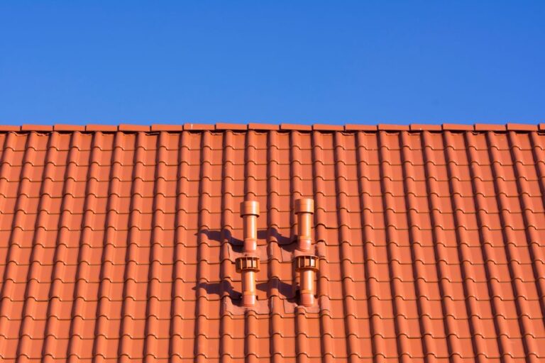 Metal step flashing visible where roof shingles meet a masonry chimney during winter weather.
