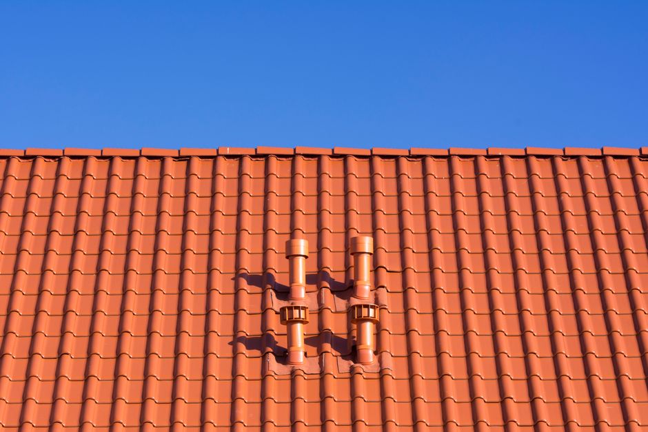 Metal step flashing visible where roof shingles meet a masonry chimney during winter weather.
